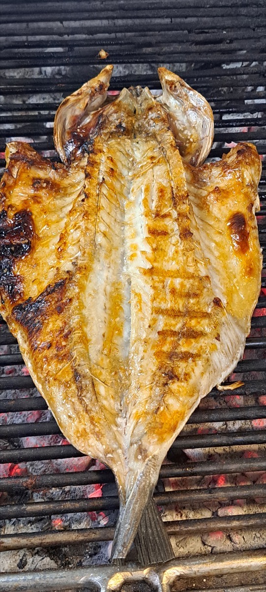 Peixe aberto a grelhar sobre a brasa